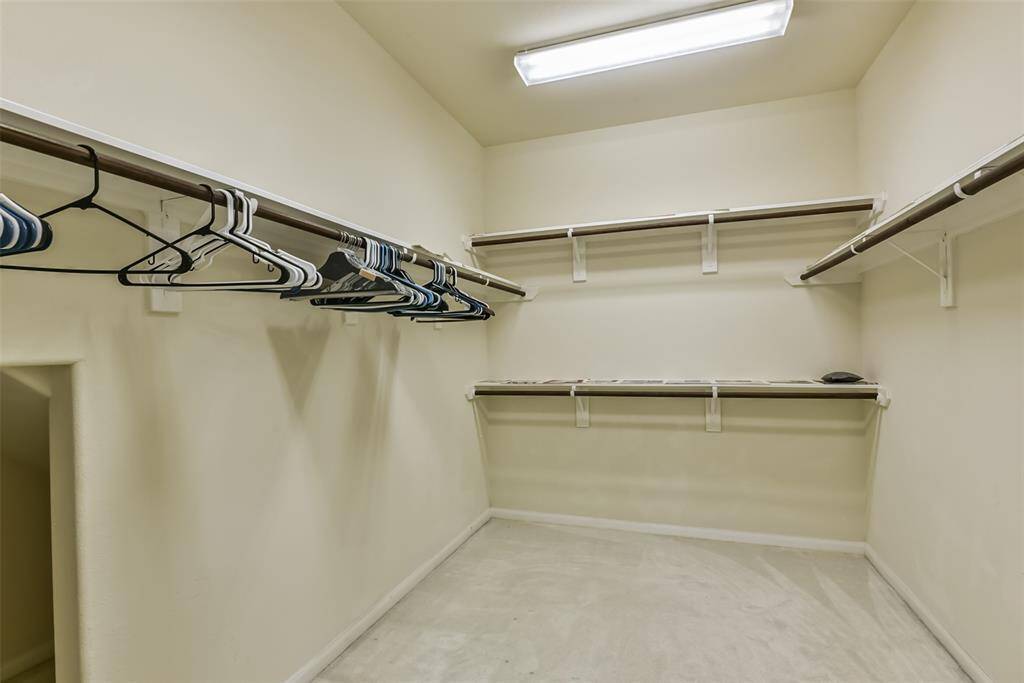 The primary walk-in closet features plush carpet and plenty of storage space.