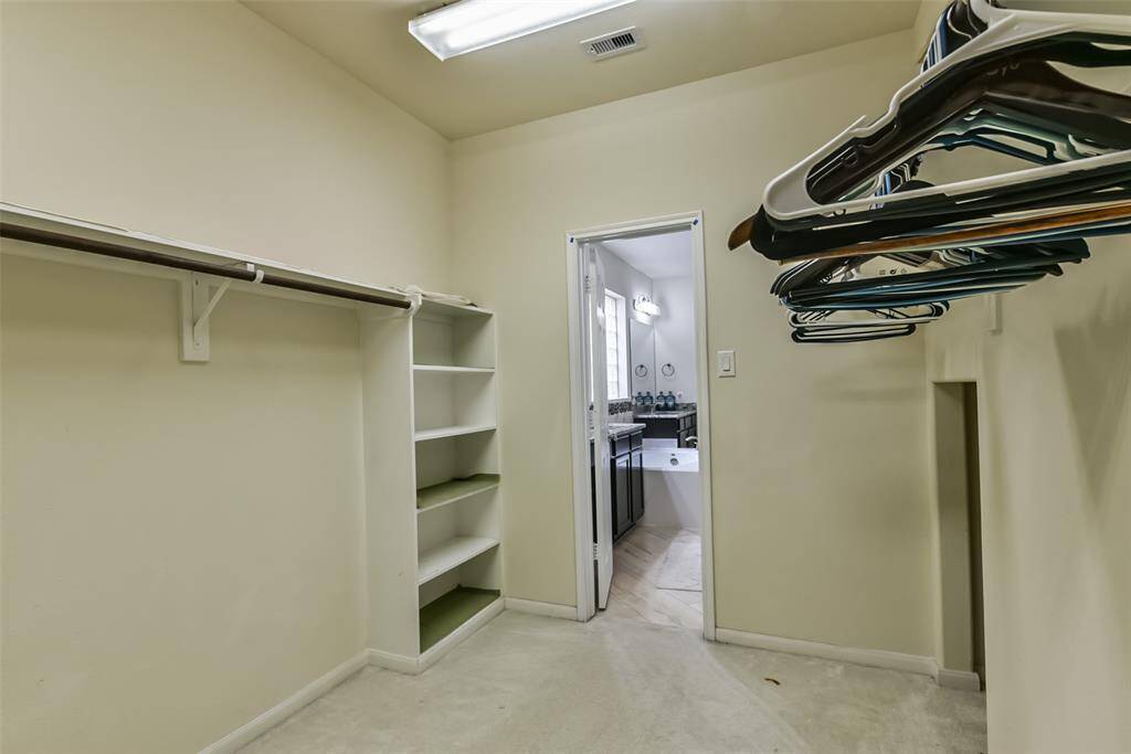 The primary walk-in closet features plush carpet and plenty of storage space.