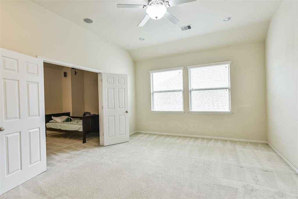 The upstairs game room features plush carpet, high ceilings, ceiling fan, and large windows.