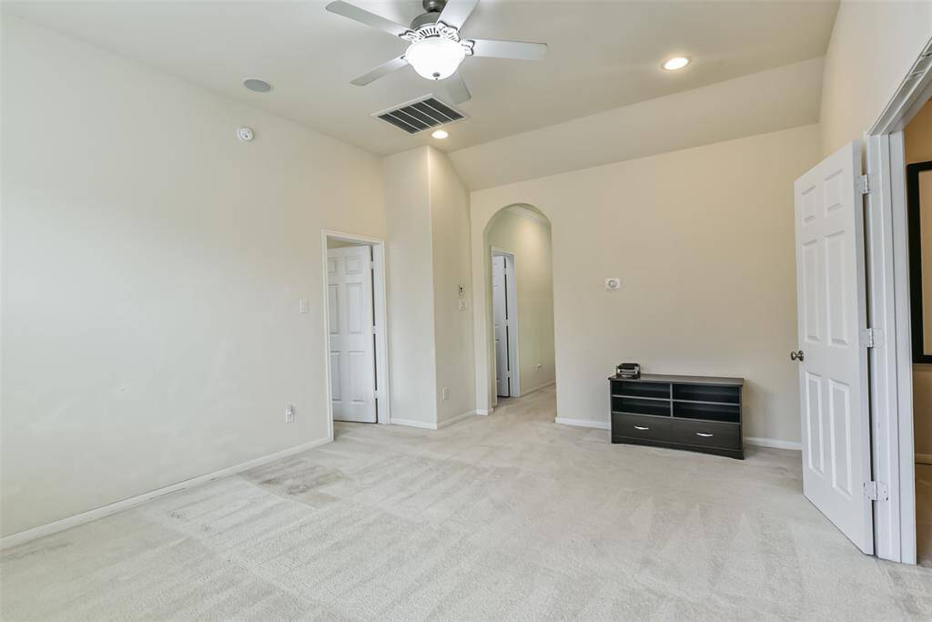 The upstairs game room features plush carpet, high ceilings, ceiling fan, and large windows.