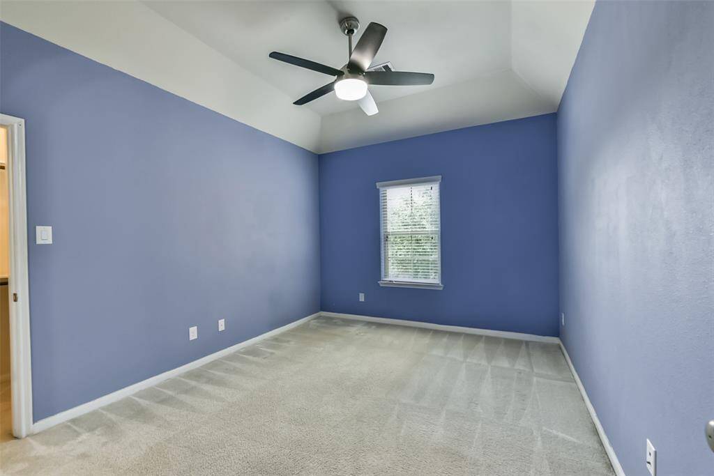 Secondary bedroom features awindow, custom paint, ceiling fan, and plush carpet.