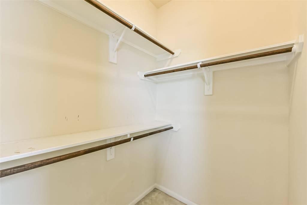 The secondary walk-in closet features plush carpet and plenty of storage space.