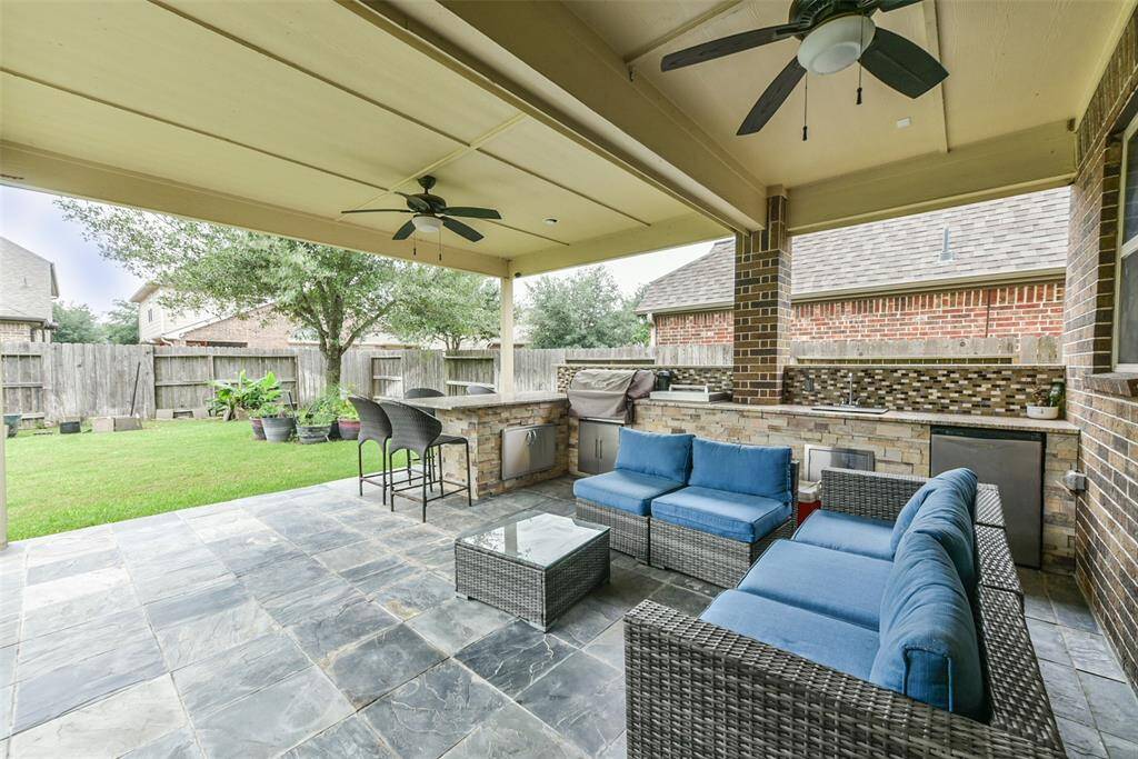 The covered patio has an outdoor kitchen with grill and stainless steel appliances.