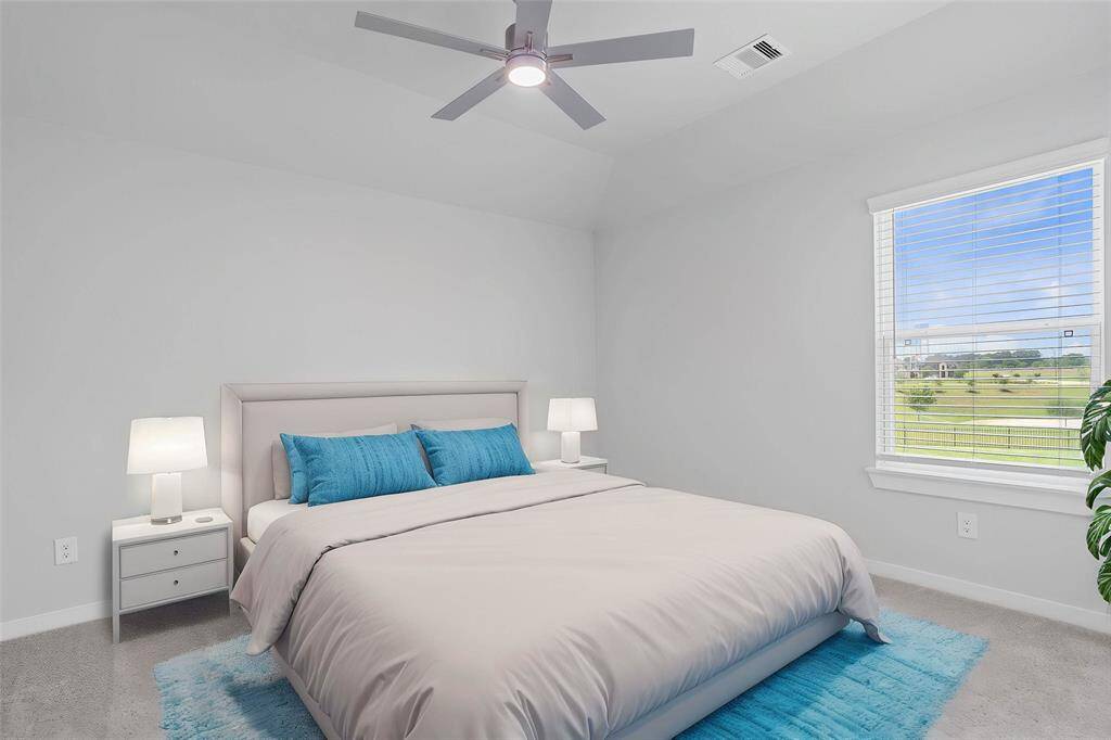 Secondary bedroom features plush carpet, custom paint, ceiling fan with lighting, closet space, and a large window with privacy blinds.