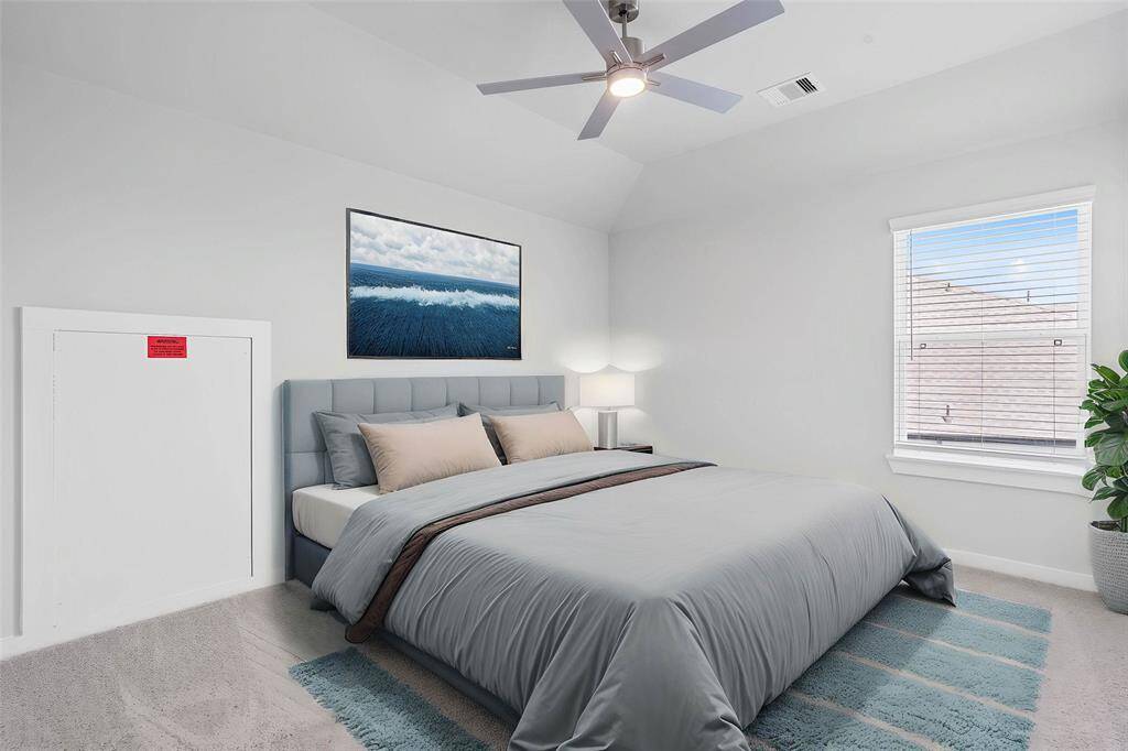 Secondary bedroom features plush carpet, custom paint, ceiling fan with lighting, closet space, and a large window with privacy blinds.
