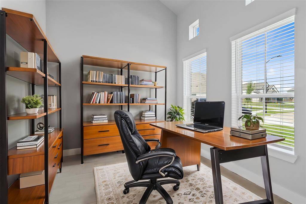 Quietly nestled in front of the home is the handsome home office. Featuring gorgeous wood look tile flooring, high ceilings, custom paint, and large windows with privacy blinds.