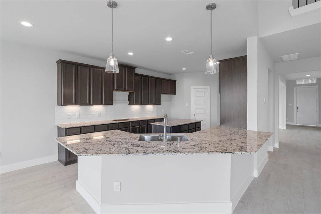 Additional view of this spacious kitchen featuring the beautiful granite countertops, pendant and under cabinet lighting.