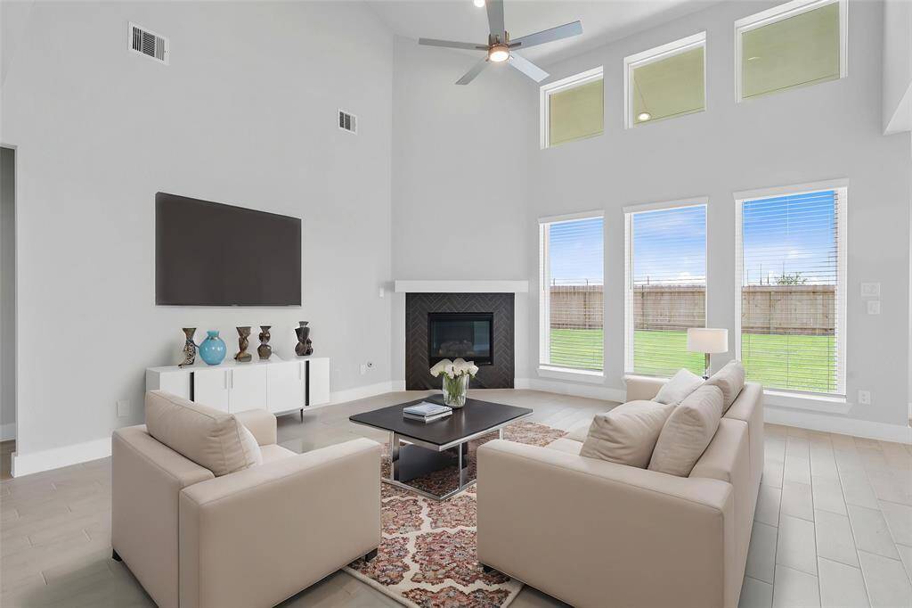 Gather the family and guests together in your lovely family room! Featuring a beautiful fireplace with wood mantel, high ceilings with ceiling fan, custom paint, gorgeous wood look tile floors and a wall of windows with privacy blinds that provides plenty of natural lighting throughout the day.