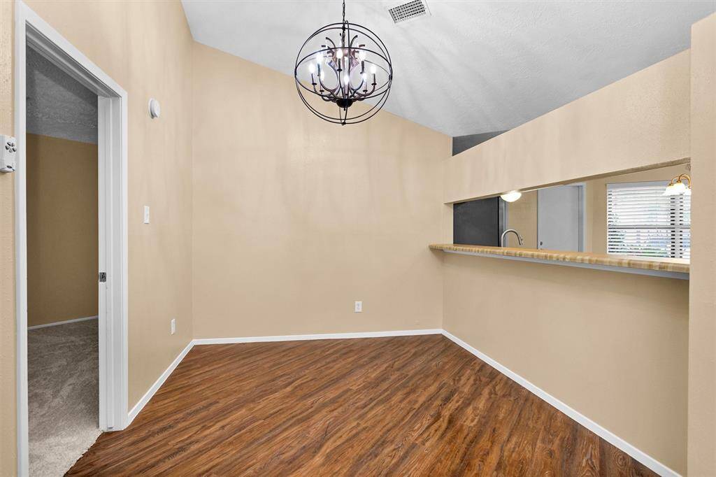 Close up and focal point of formal dining with contemporary geometric chandelier and a 9 ft bar opening to kitchen.