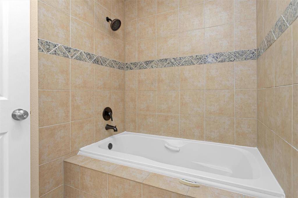 Therapeutic air jetted spa-like tub with automatic drying feature surrounded by upgraded coordinating tile and granite for tub surround.