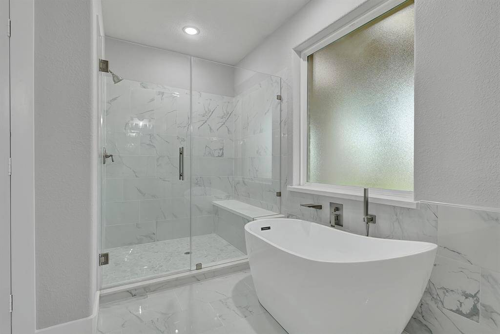 Garden tub and separate shower with frameless shower door and sitting area.