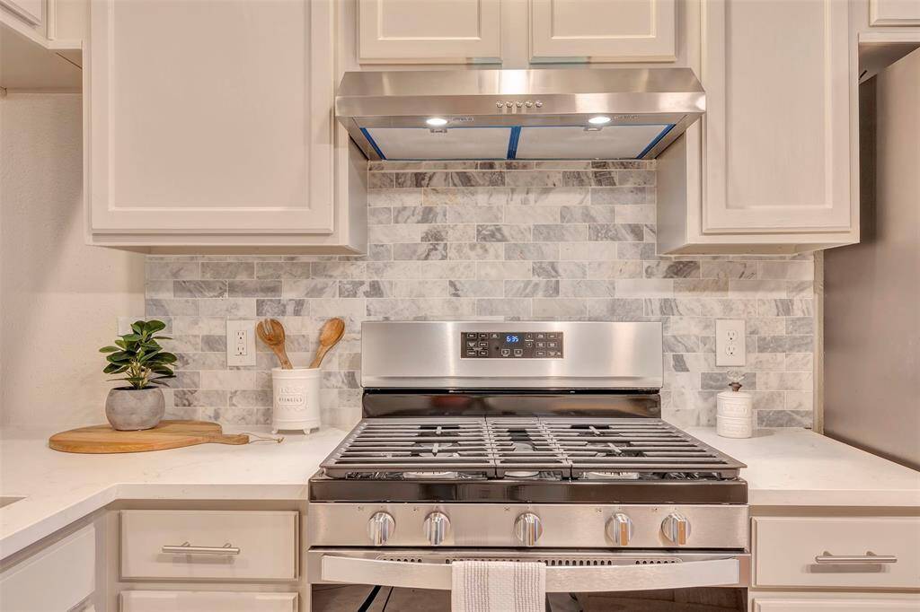 Updated kitchen featuring modern countertops, stylish backsplash, new stove, and a brand-new dishwasher.