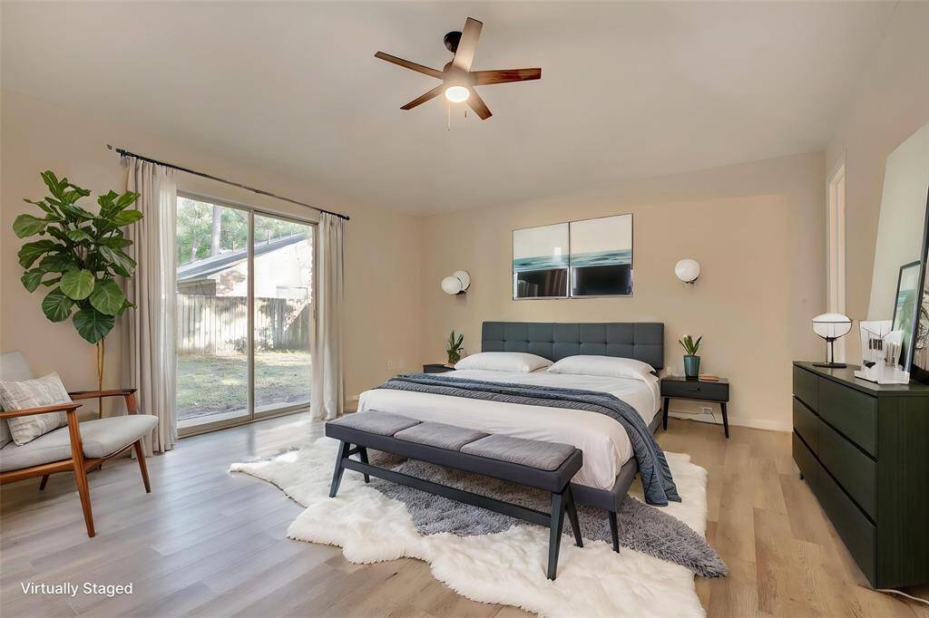 Virtually staged primary bedroom featuring sliding patio doors with a view of the backyard.