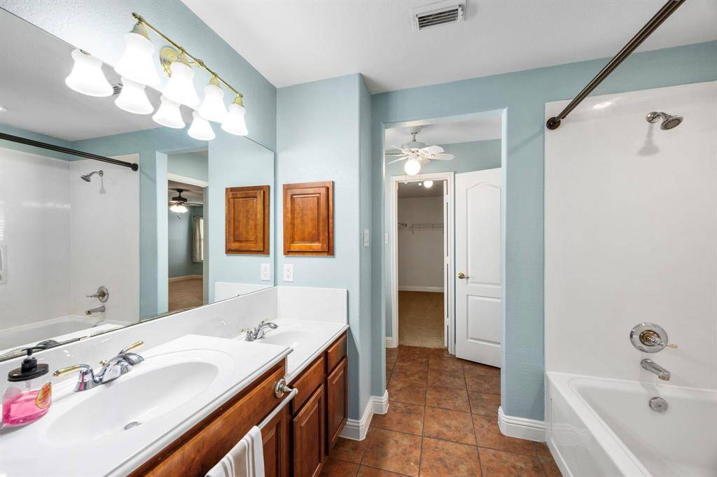 Primary bathroom features double sinks, a sitting area with fan, and an oversized soaking tub.
