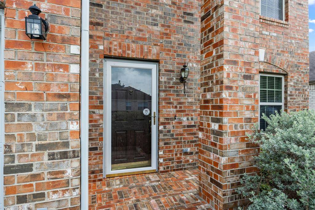 Entry features full brick porch, glass door and dark wood stained door.