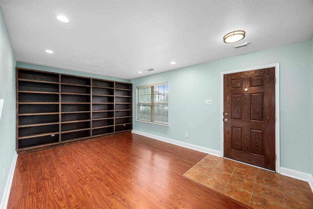 Full wall of built-in shelving makes this the perfect office/study area. Or imagine a sitting room, watching the hummingbirds and butterflies through the front window while you drink your morning brew.