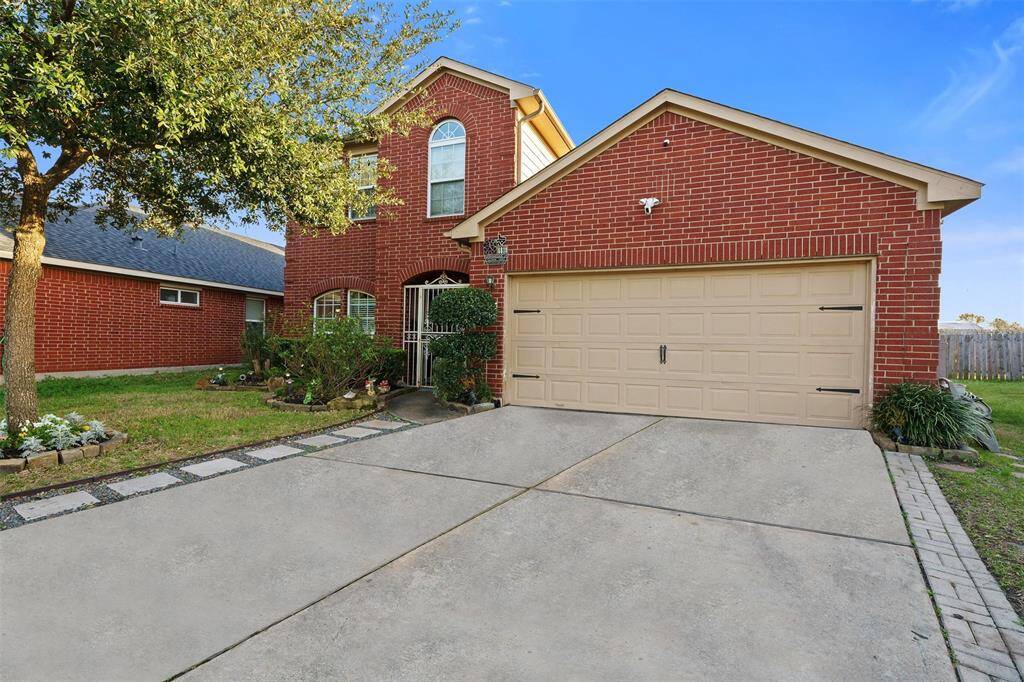 This two-story brick home features a two-car garage, a spacious driveway, and a well-maintained front yard with mature landscaping.