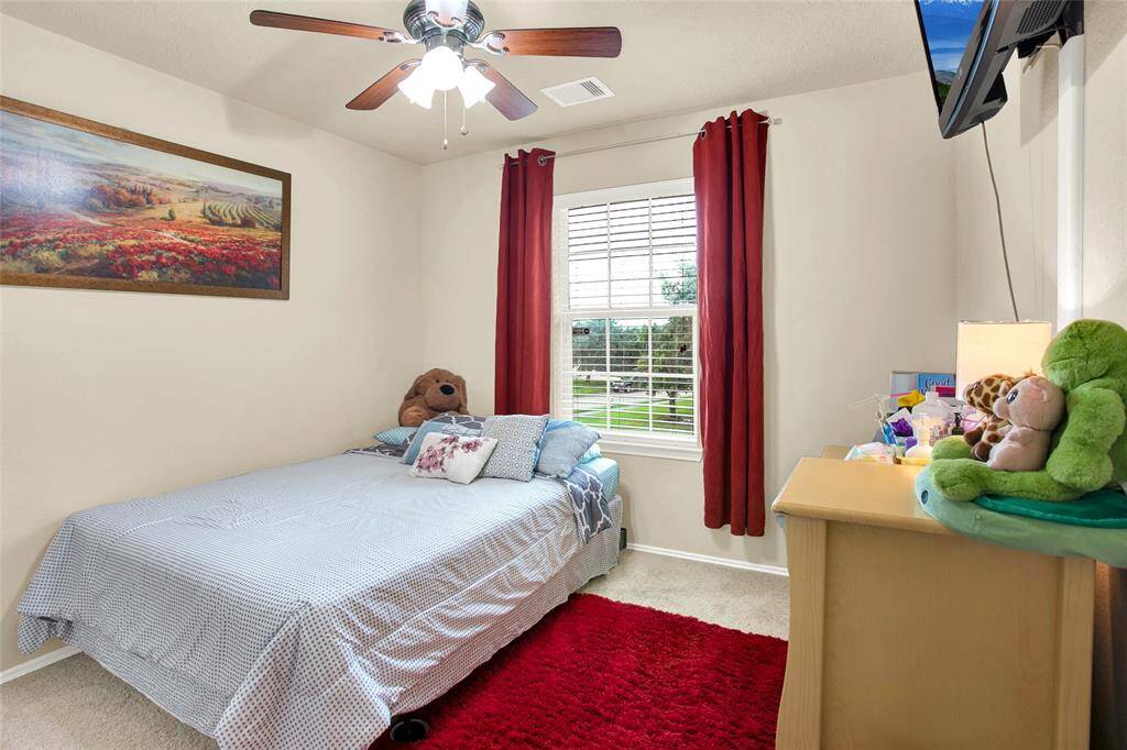 Discover serenity in this inviting bedroom, bathed in natural light, featuring a soothing ceiling fan, luxurious carpet, and a charming window view that ensures a restful retreat.