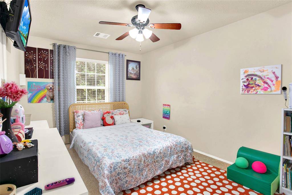 Discover a welcoming bedroom bathed in natural light with a charming ceiling fan and plush carpeting, ideal for a child's oasis or a welcoming guest retreat.