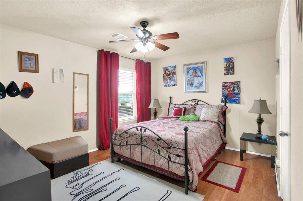 Discover a serene, inviting bedroom oasis, boasting gleaming hardwood floors, a refreshing ceiling fan, and a flood of natural light from generous windows.