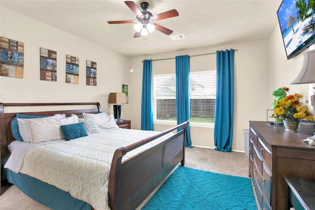 Discover serene comfort in this bright, inviting bedroom, complete with a refreshing ceiling fan and charming decor.
