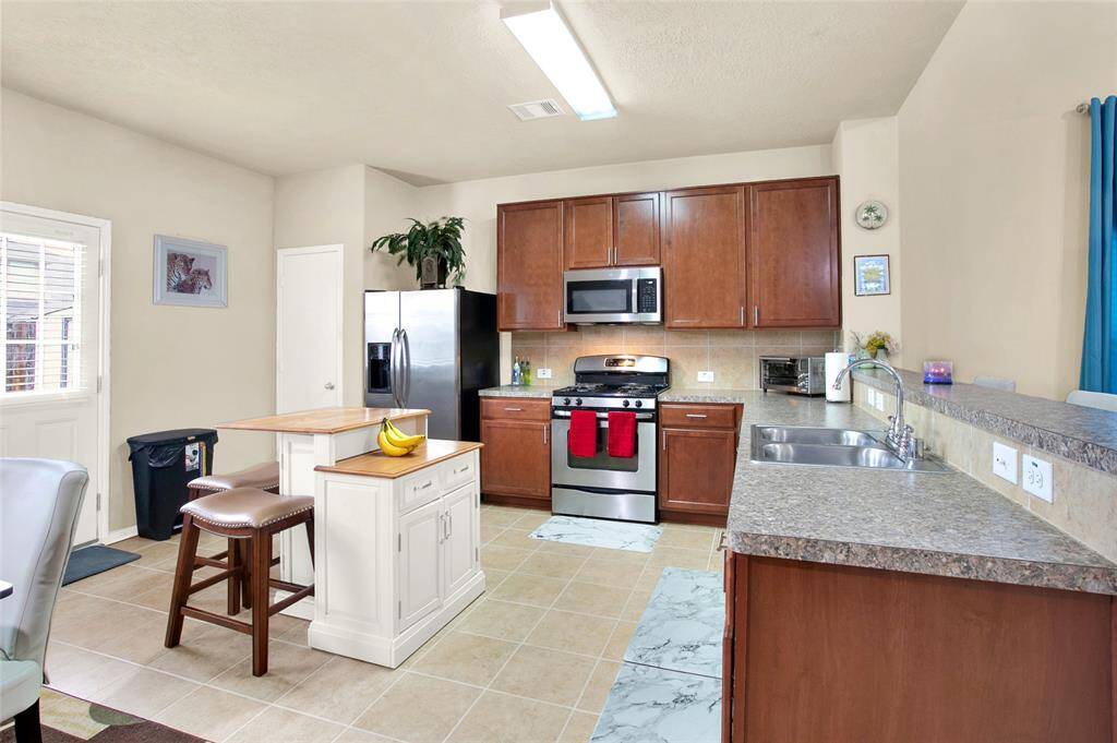 Discover the heart of your new home in this beautifully lit, expansive kitchen, boasting sleek modern appliances and generous cabinet storage. The tasteful neutral palette and elegant tiled floors complete this perfect culinary canvas.