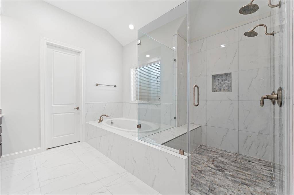 Spa-like primary bath with double sinks and dual shower heads.