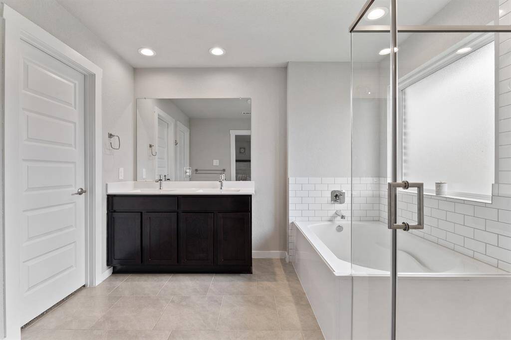 The primary ensuite features dual sinks, a soaking tub, a separate shower, and a private water closet for added convenience. A spacious walk-in closet completes the retreat, offering ample storage and organization.