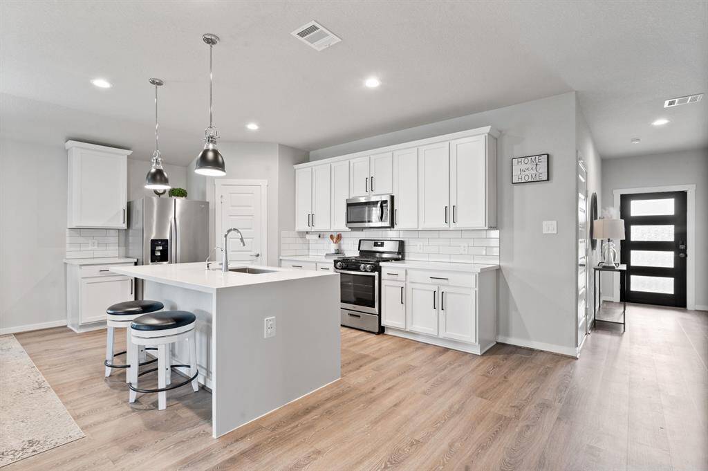 This island kitchen features a convenient breakfast bar, modern appliances, and ample counter space walk-in pantry and abundant cabinetry provide plenty of storage, combining style and functionality in one central hub.