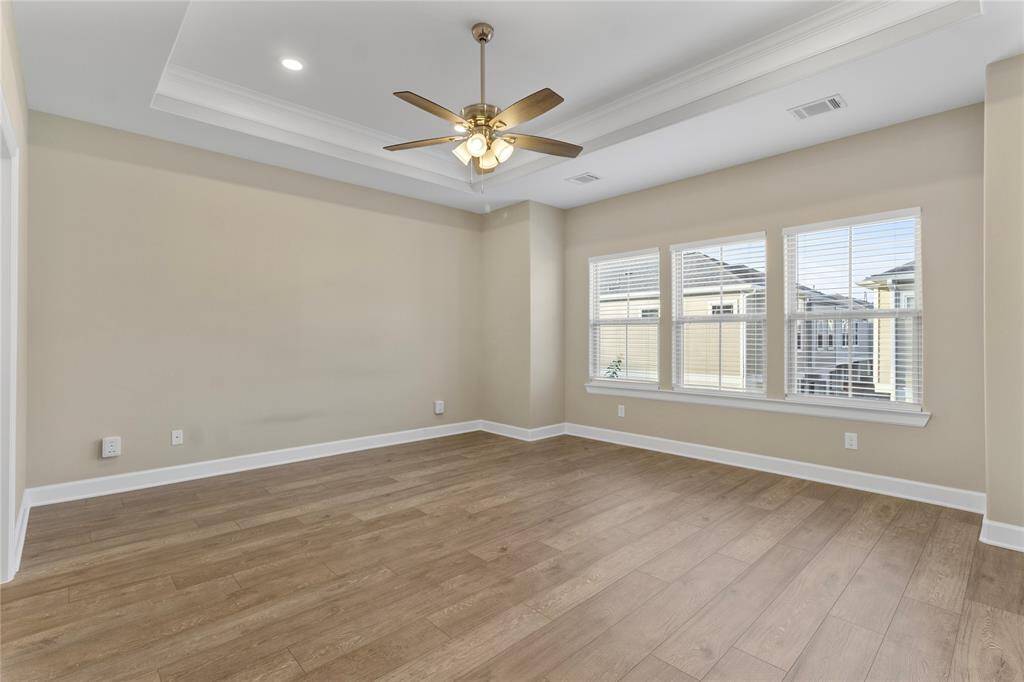 Spacious primary bedroom with elegant tray ceilings and abundant natural light.