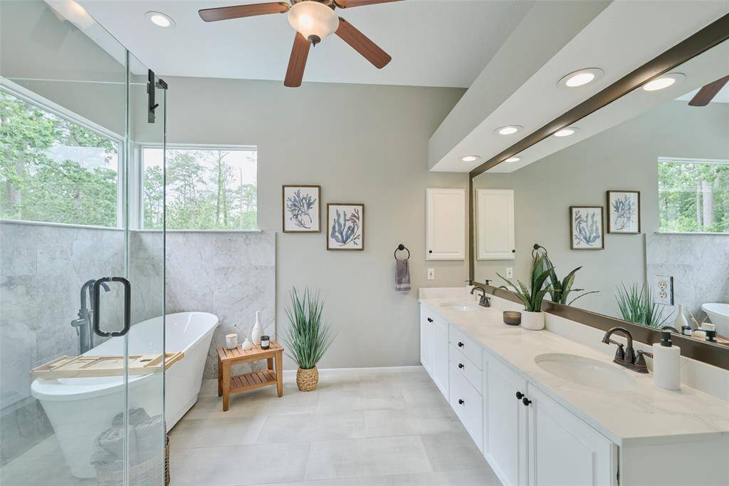 The serene spa like primary bath  brings the outside in with picture windows of the lush tree line. The sunsets from this view are magical.