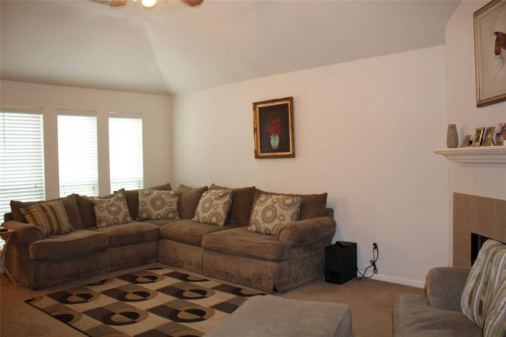 Living room has triple windows, vaulted ceiling with fan, and gas fireplace.