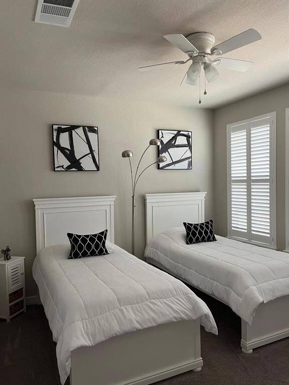Second bedroom downstairs with carpet and window shutters.