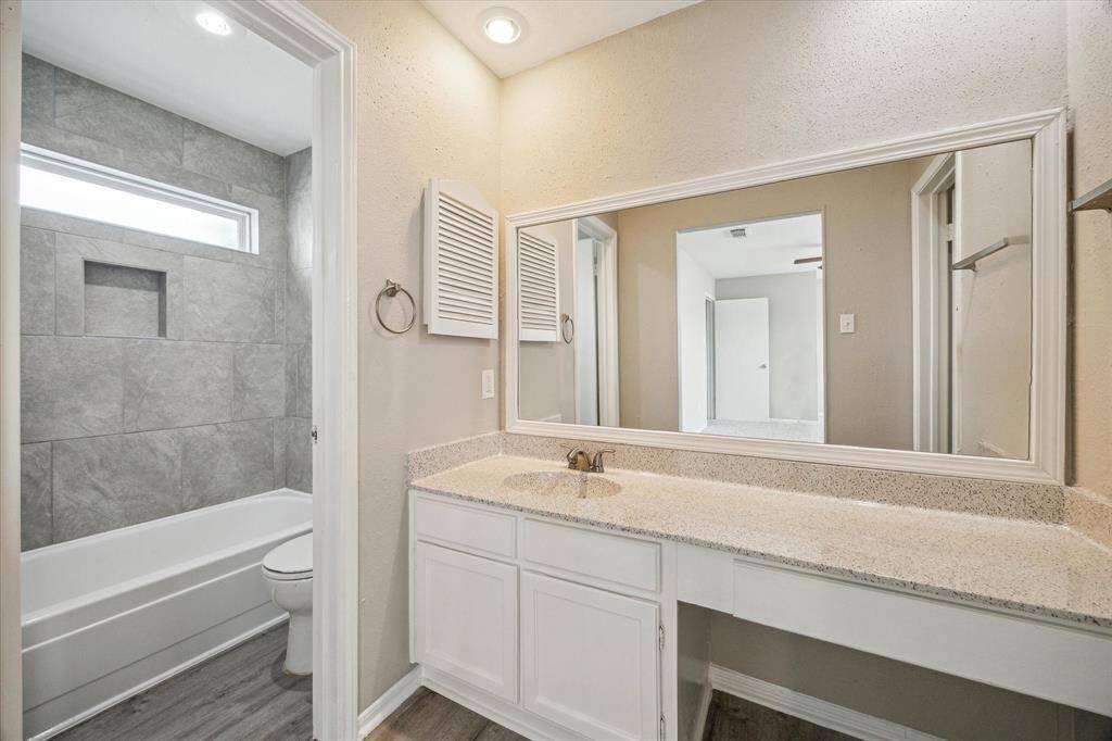 The primary suite has an extra space on the counter for a makeup nook. There is a walk in closet next to the vanity. The bath tub has been refinished, and tiled to the ceiling, and fresh paint can be seen throughout the home.