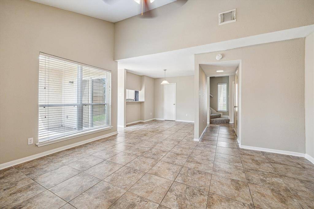 A view from the living room to the hallway leading to the half bath and dining area, with a partial view of the staircase.