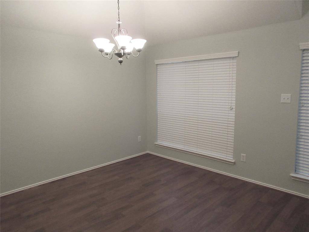 The dinning room features a modern chandelier, and large windows with blinds, offering a bright and inviting space.