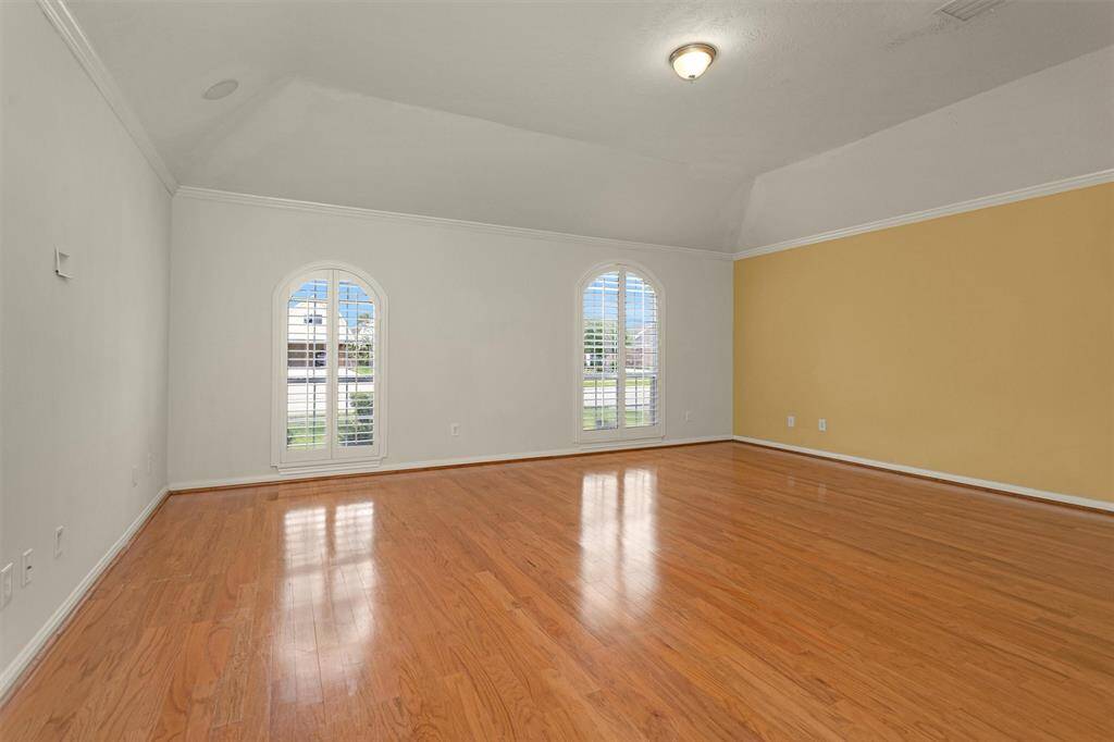 Step into the oversized Primary Suite! Featuring hardwood floors and two large, arched windows filling the room with natural light!