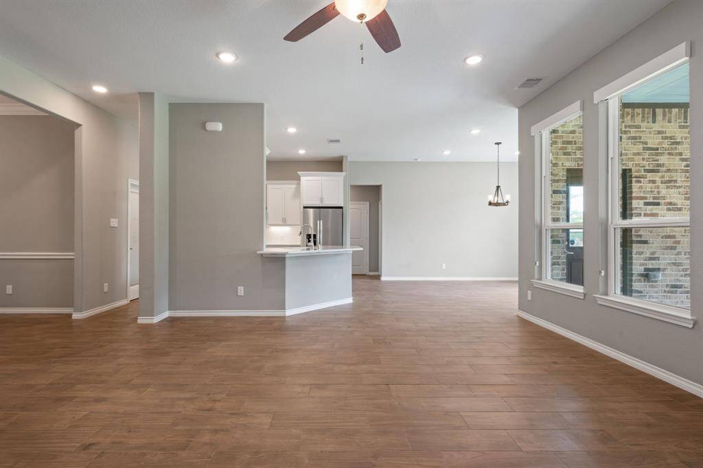 Open-concept living flows into a bright kitchen with bar seating, pendant lighting, and serene backyard views.