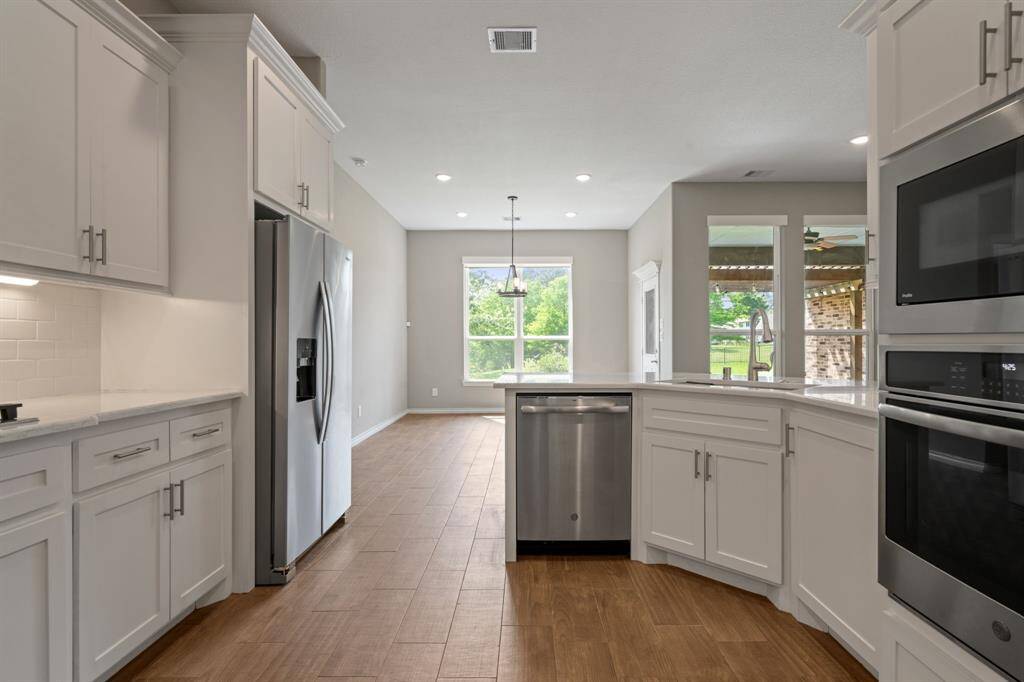 Light-filled kitchen with expansive counter space, stainless dishwasher, and open layout for entertaining.