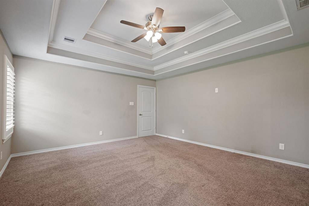 Retreat-style primary bedroom with ceiling fan, crown molding, and tranquil atmosphere.