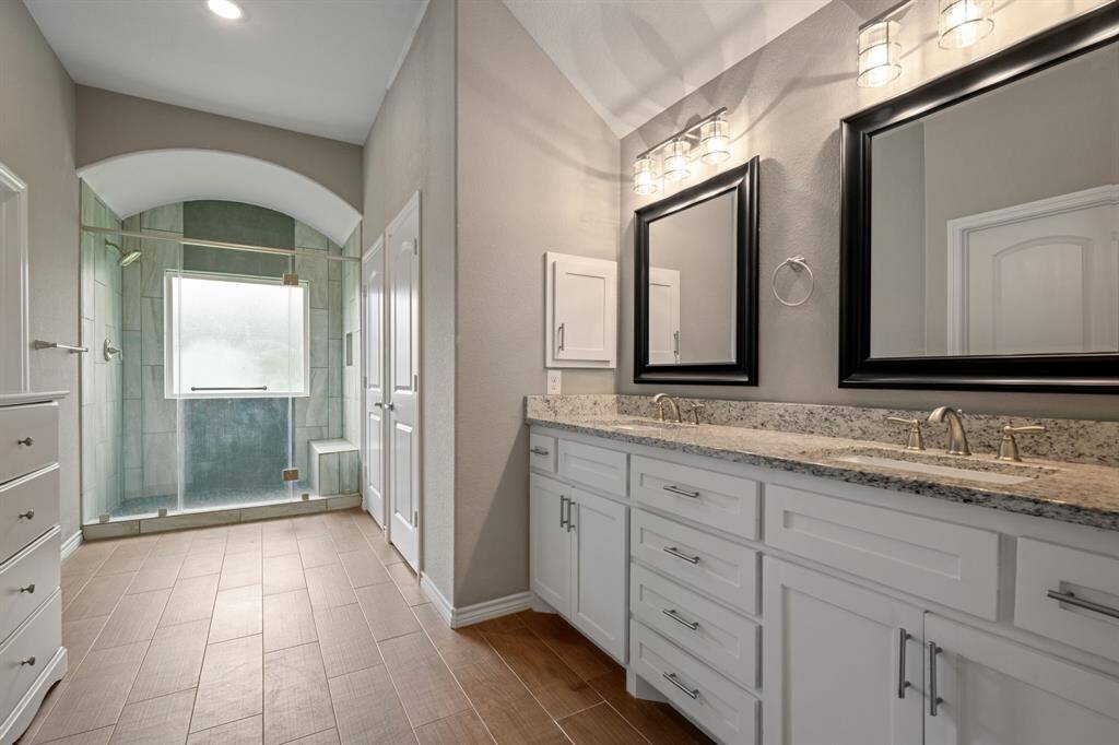 Elegant spa-inspired bath featuring dual sinks with granite counters, framed mirrors, and designer lighting.