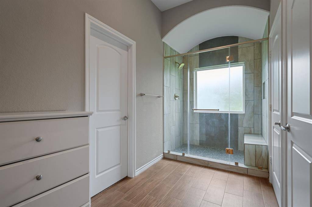 Luxurious walk-in shower with arched ceiling, seating bench, and frosted privacy window.