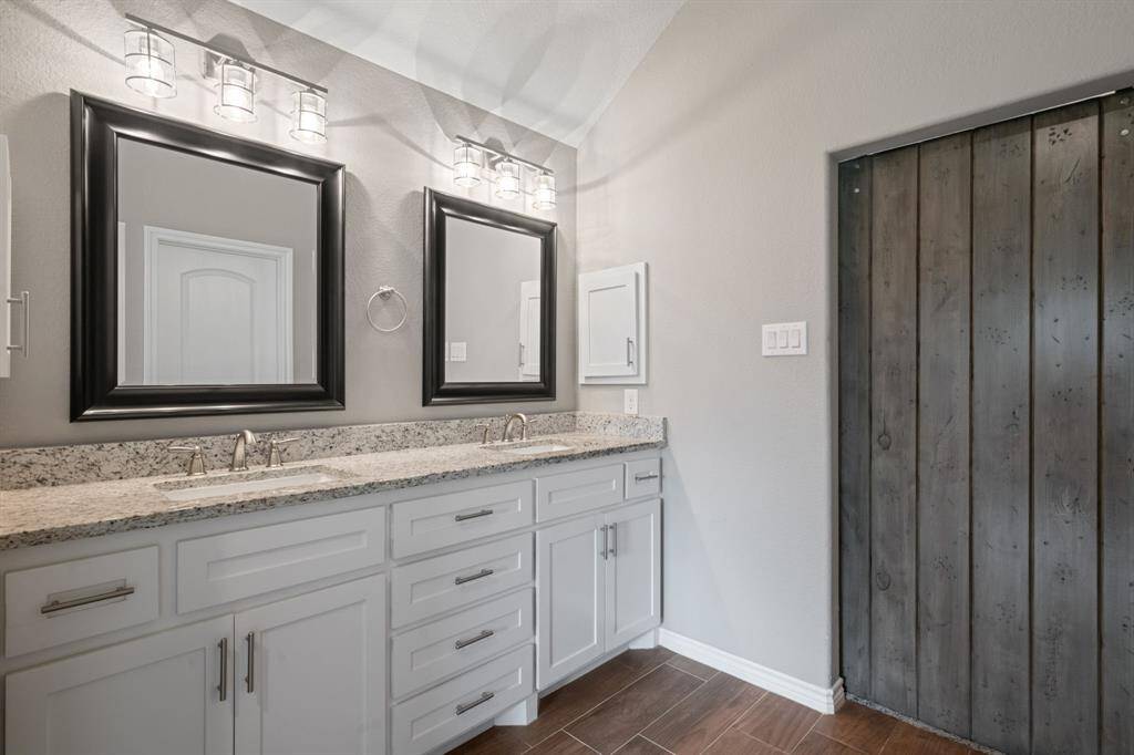 Double vanities offer ample storage and style, beautifully accented by the rustic barn door entry.