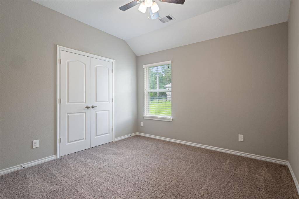Comfortable secondary bedroom with plush carpet, ceiling fan, and large closet—perfect for guests or family.