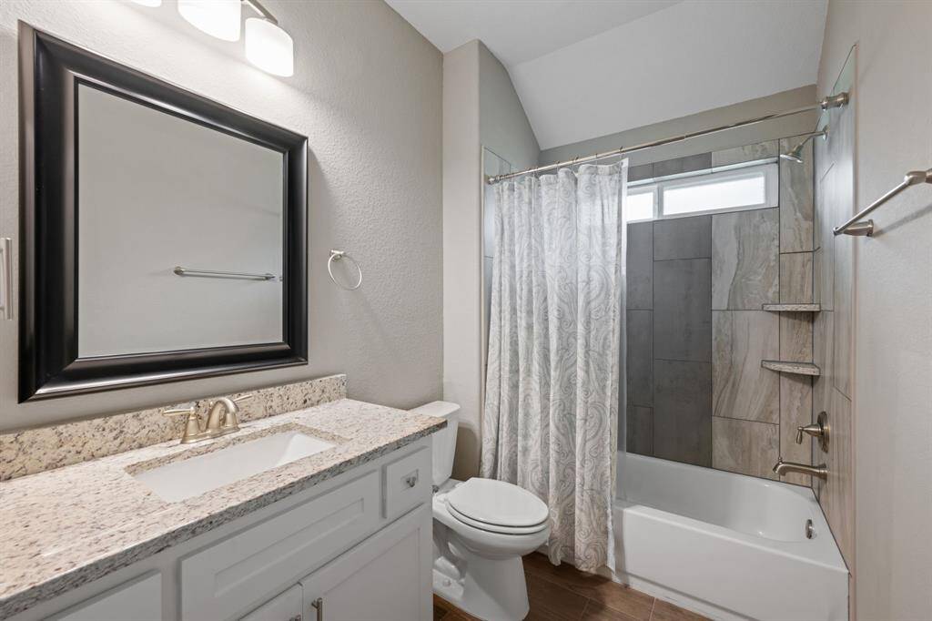 Stylish guest bathroom with granite vanity, upgraded lighting, and fully tiled shower/tub combo.