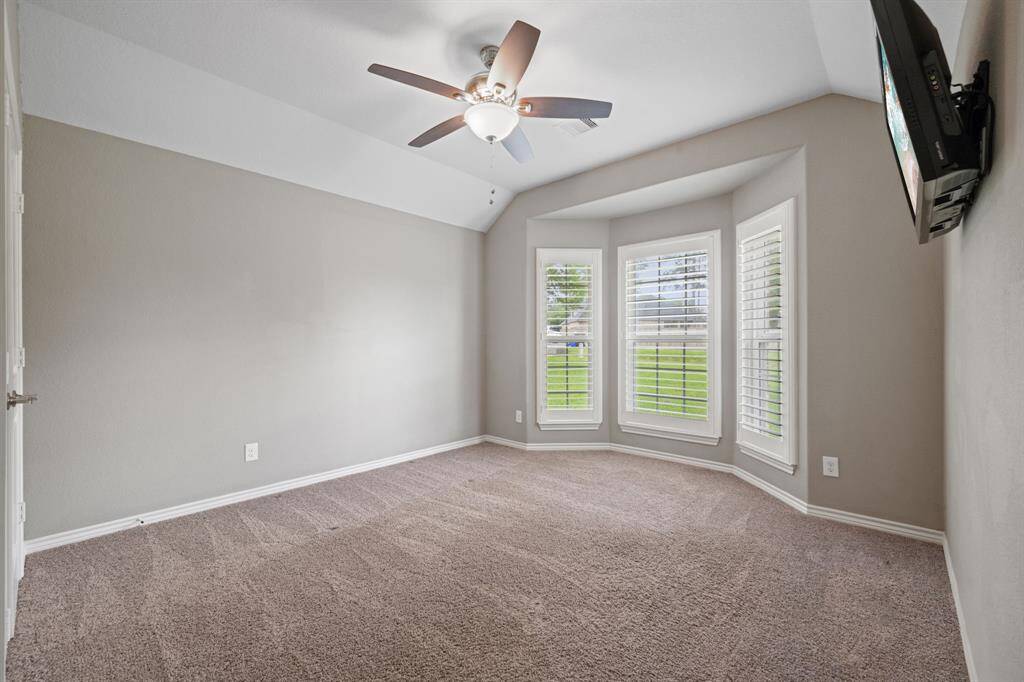 Charming bedroom with a bay window, plantation shutters, and ceiling fan—ideal for a study or nursery.