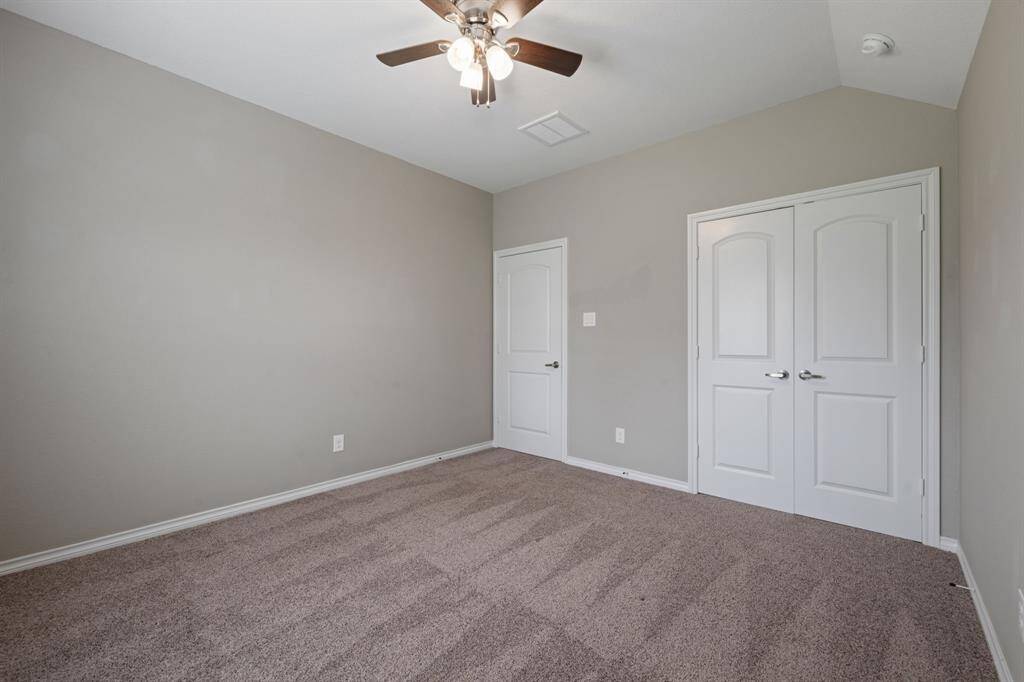 Versatile third guest bedroom with soft carpet, high ceiling, and tranquil backyard view.