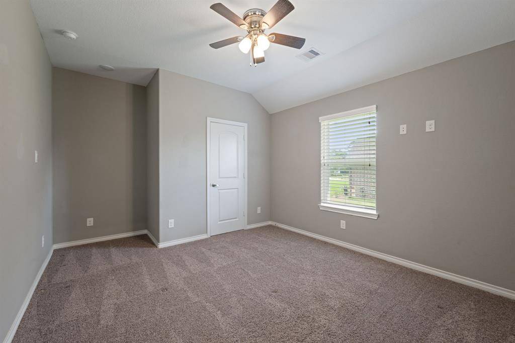 Spacious secondary bedroom with ceiling fan, fresh paint, and natural light pouring in through the window.