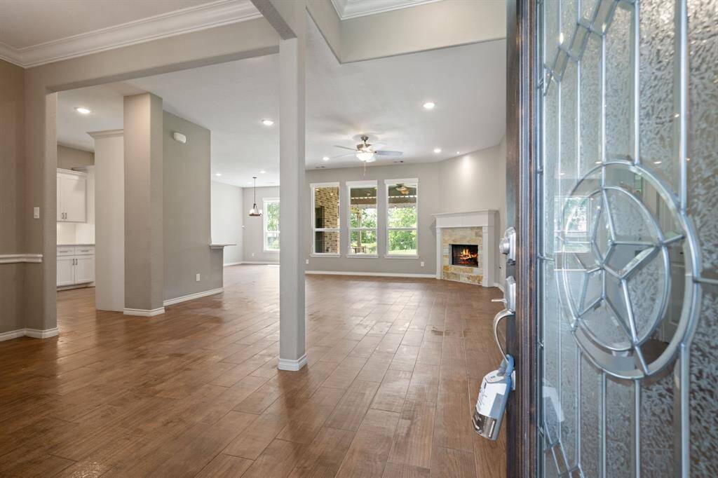 Step inside to an open concept layout with wood-look tile, crown molding, and views of the backyard oasis.