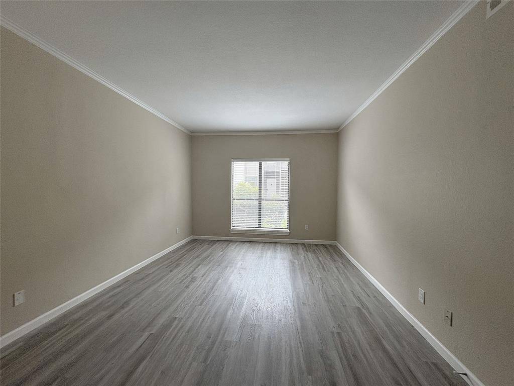 Spacious primary bedroom has two walk-in closets, and a large window overlooking natural scenery outside the condo.